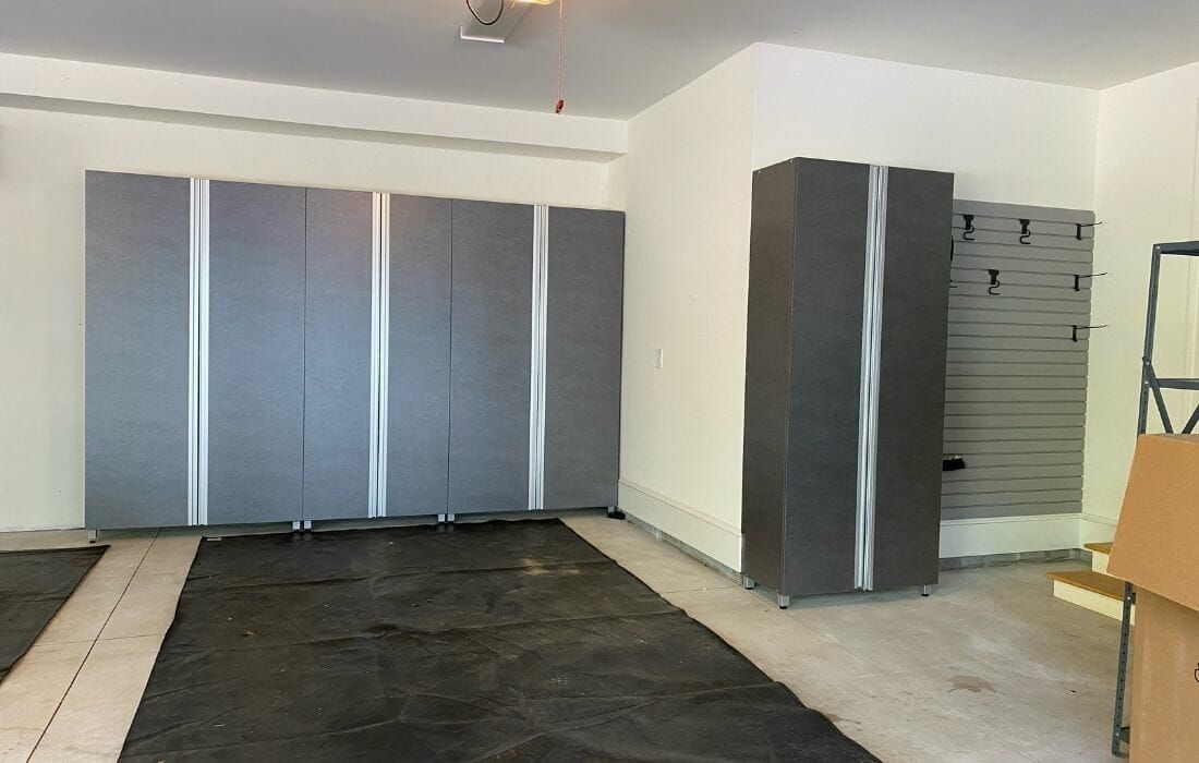 Spacious garage storage system featuring tall gray cabinets with sleek aluminum handles and wall-mounted tool organizers.