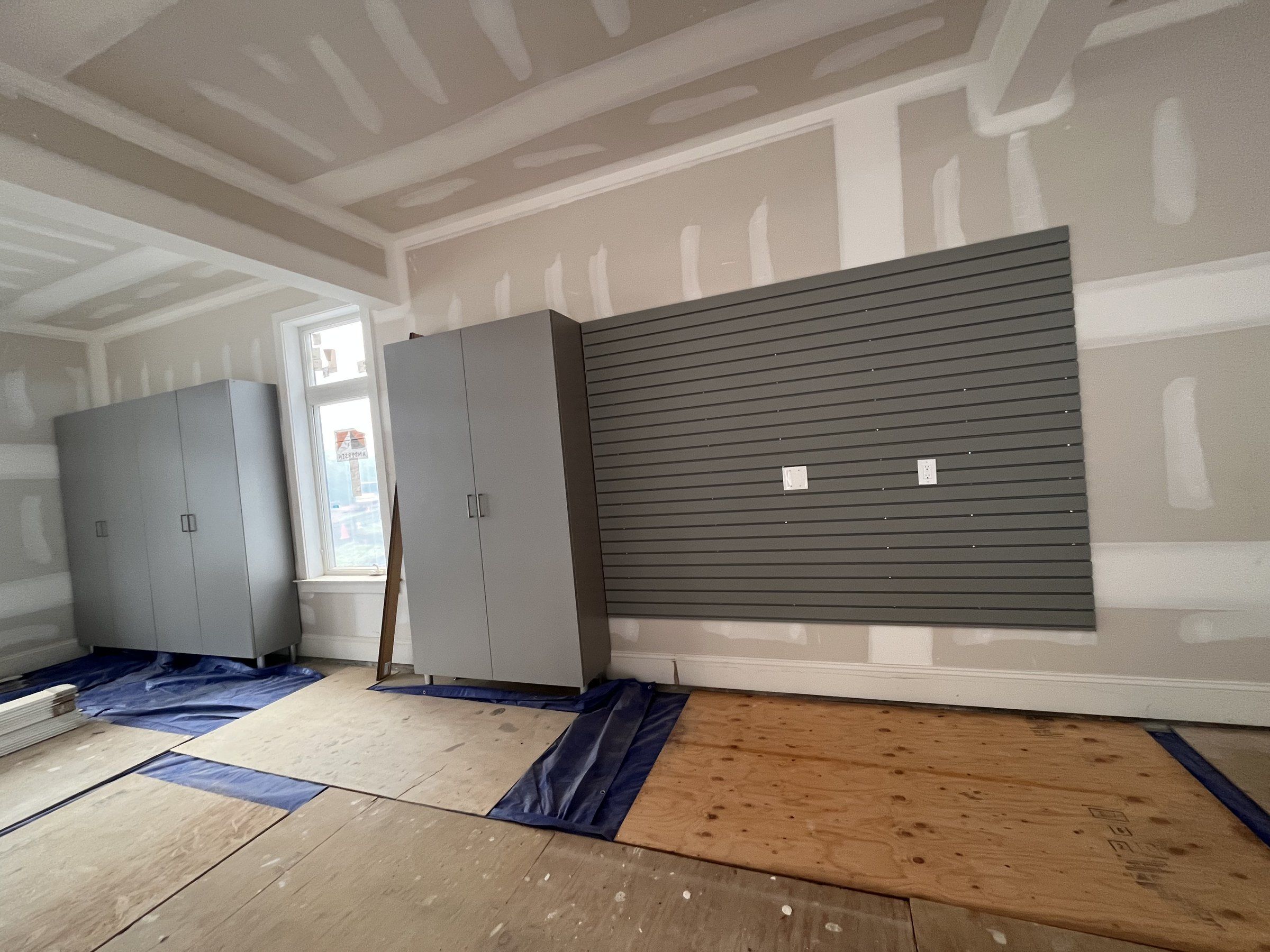 Garage storage with gray slatwall panels and tall cabinets during installation