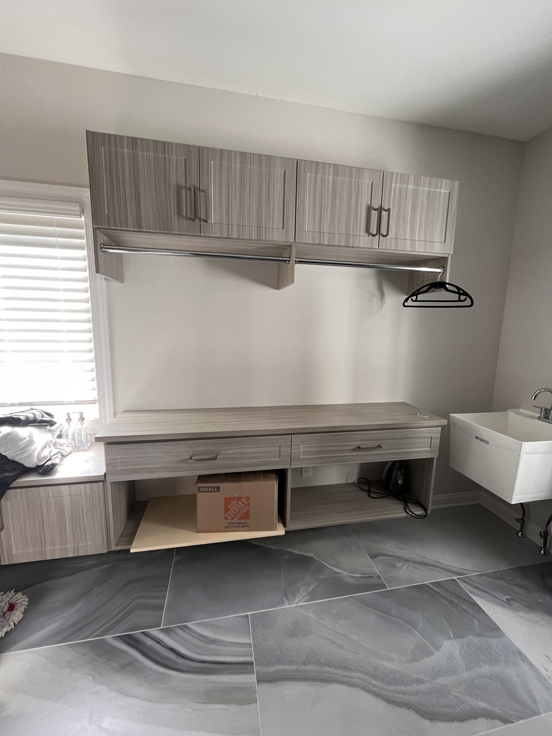 Laundry room with wood-grain upper cabinets, a hanging rod and a folding counter