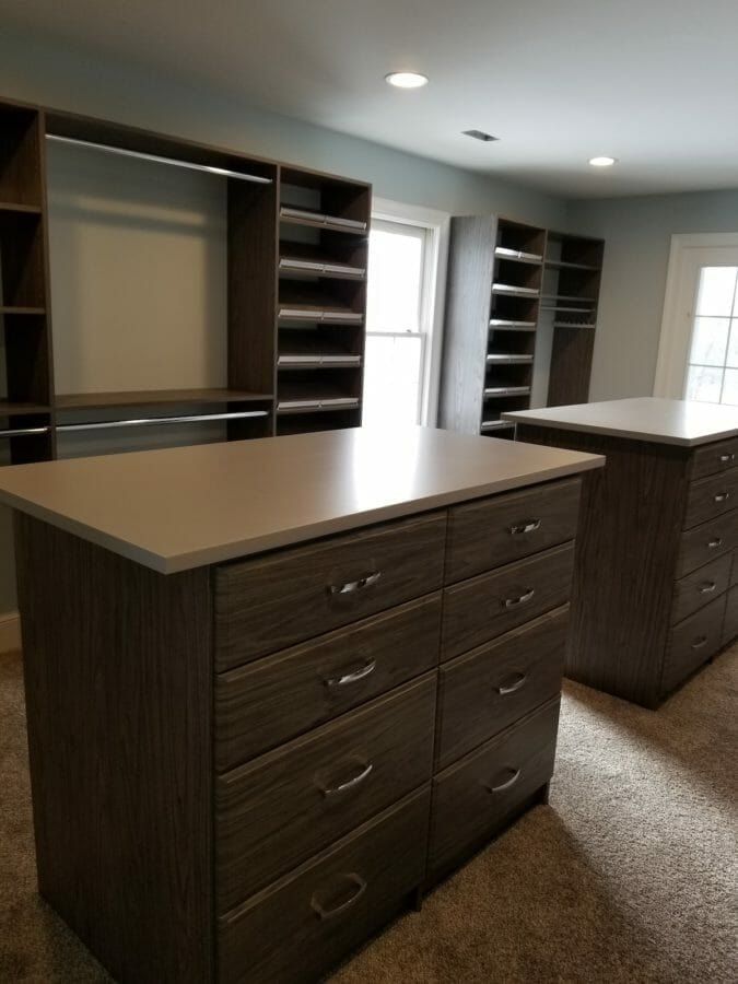 Two wood-grain drawer islands in a walk-in closet