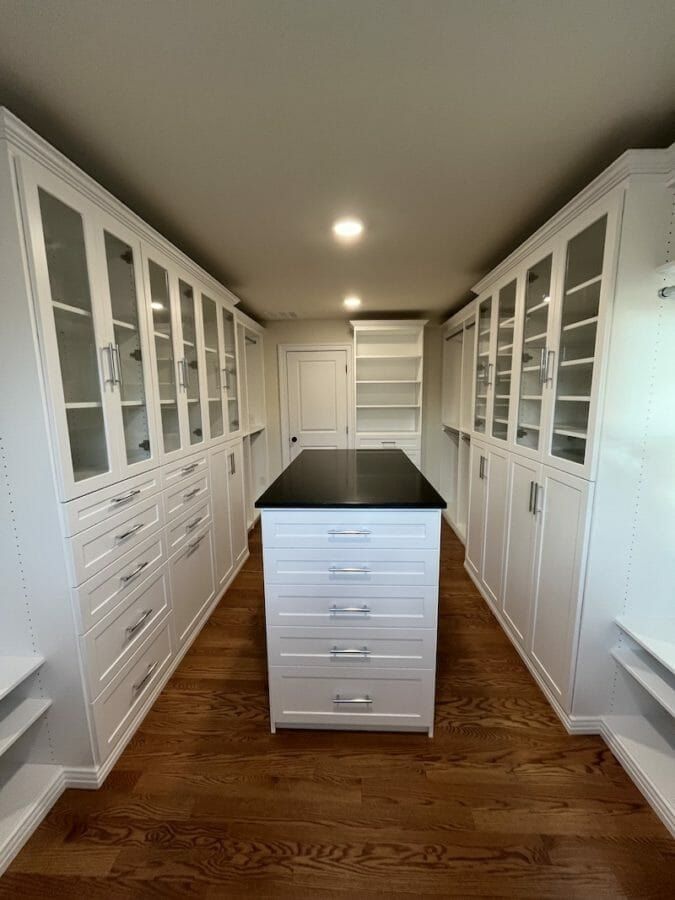 Walk-in closet with glass-door cabinets on both walls and a center island