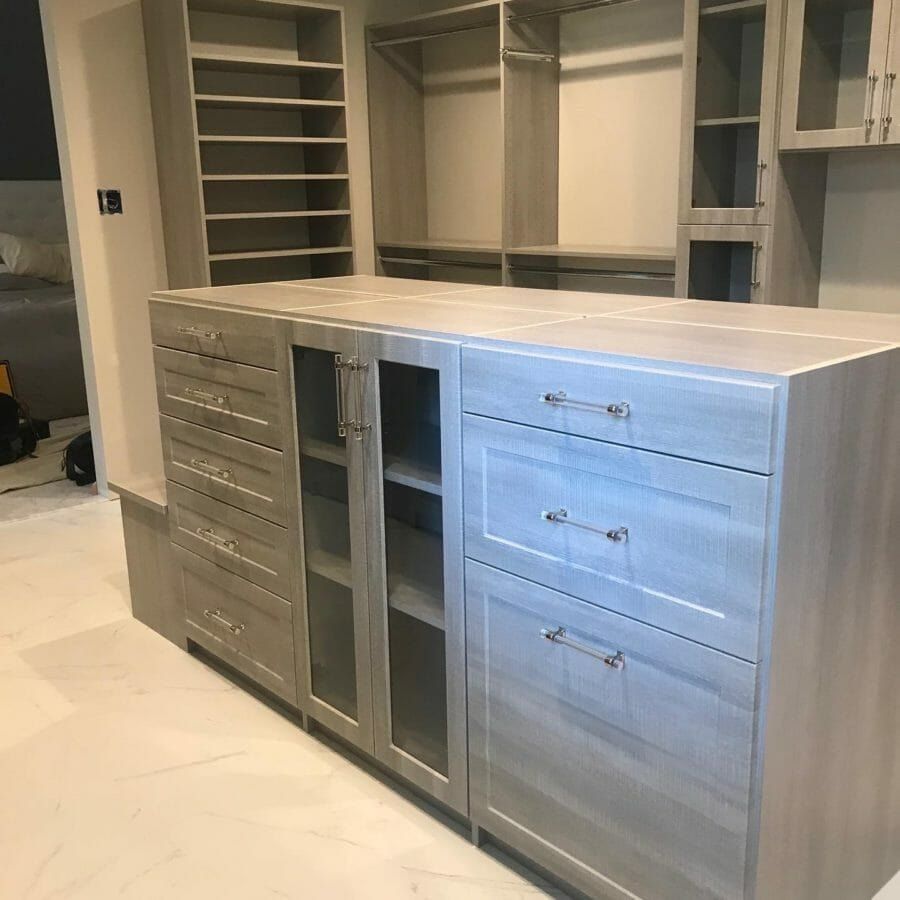 Walk-in closet gray island glass cabinets, installed by Closets For Less