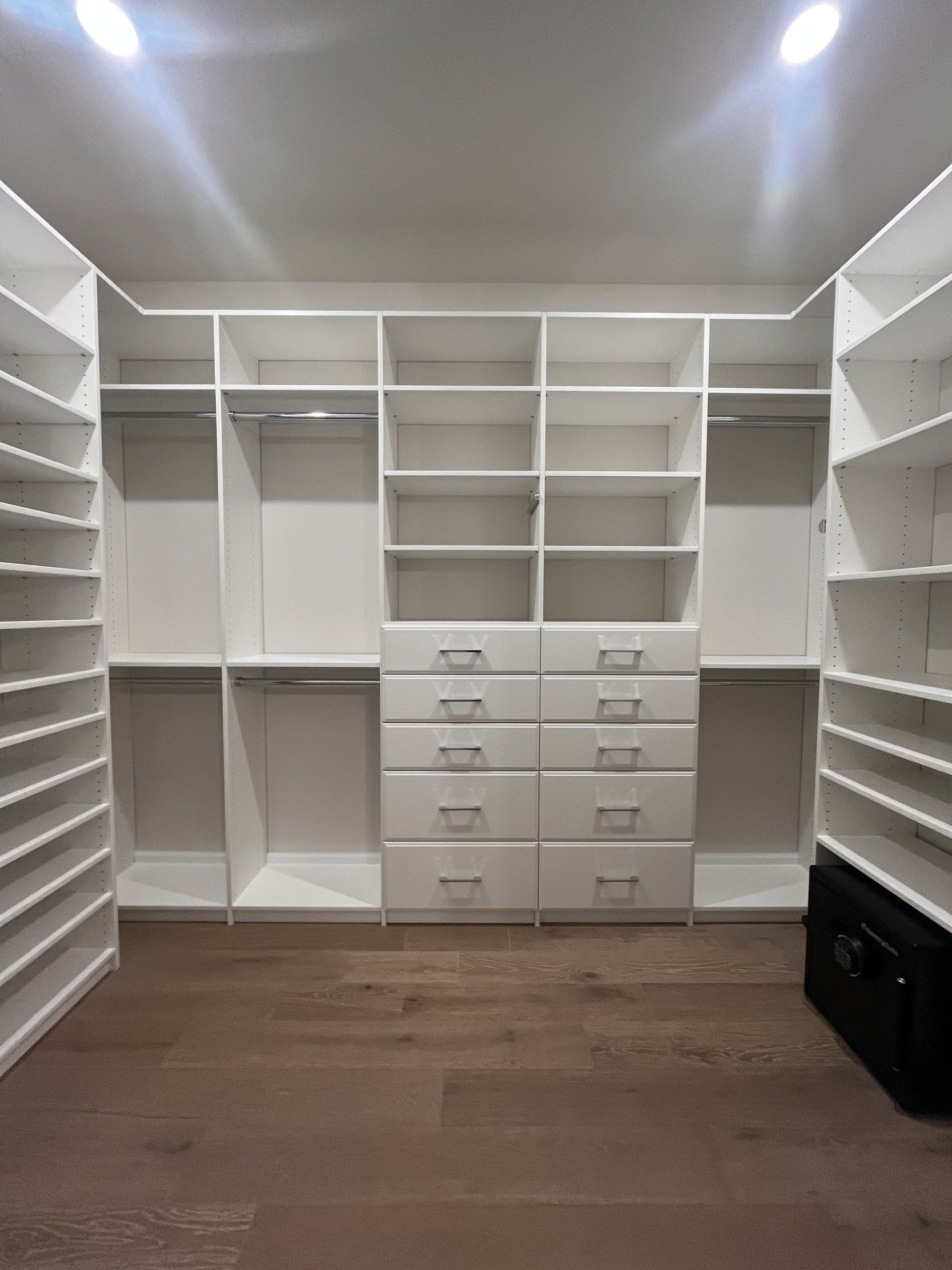 White custom walk-in closet with a center drawer tower, shoe shelving and double-hang rods